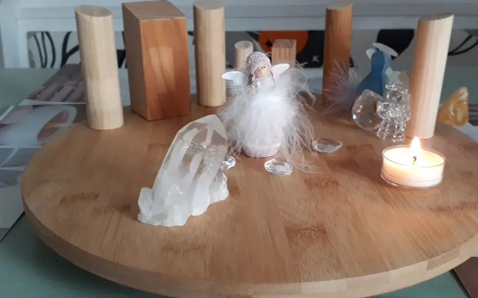 Das Aufstellungsbrett mit Holzfiguren, Bergkristallen, einer Engelfigur und einer Kerze