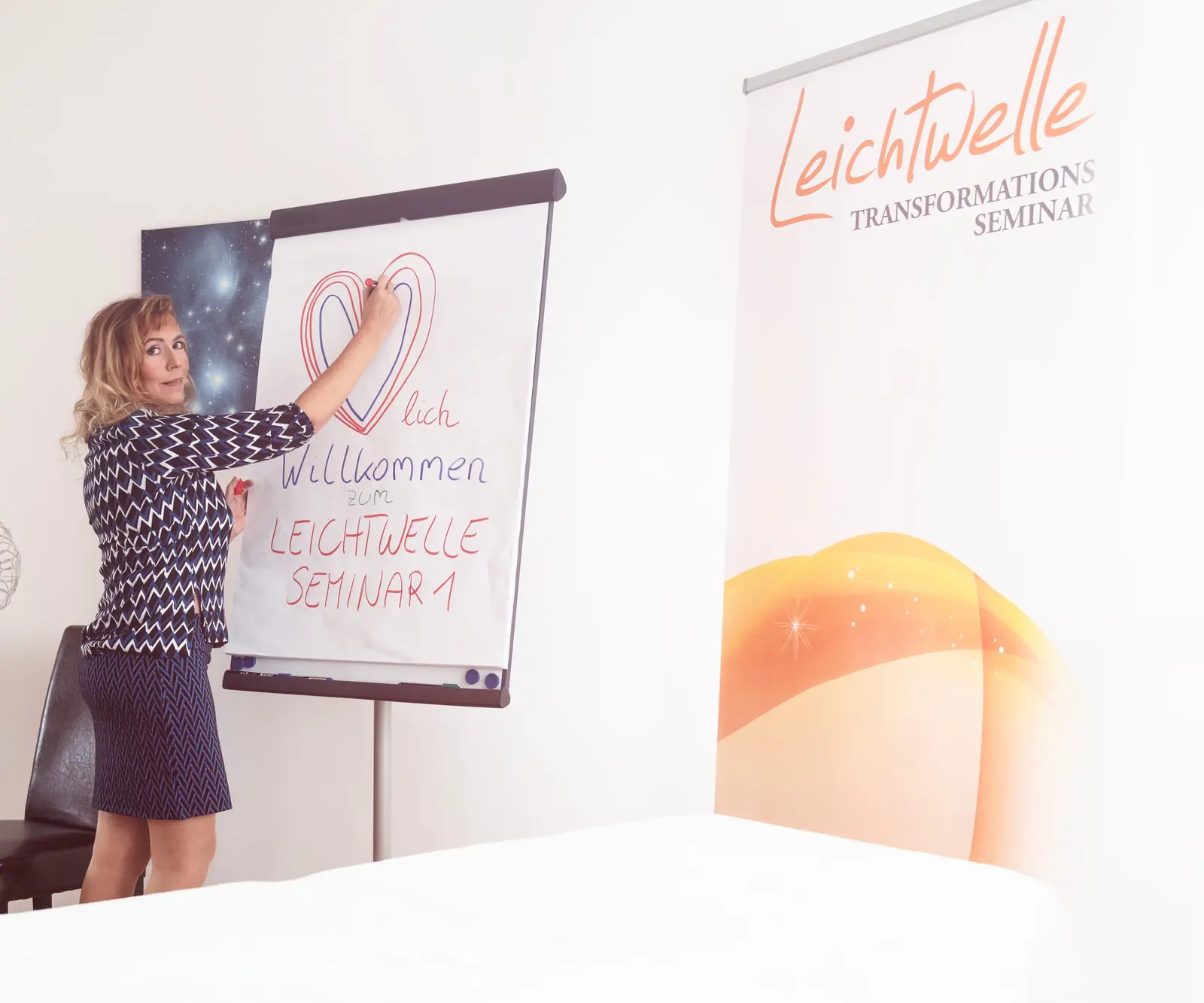 Seminarraum mit Flipchart „Willkommen Leichtwelle Seminar 1“ und Roll-up-Banner